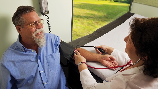 Man sitting down and having his blood pressure taken by a clinician.